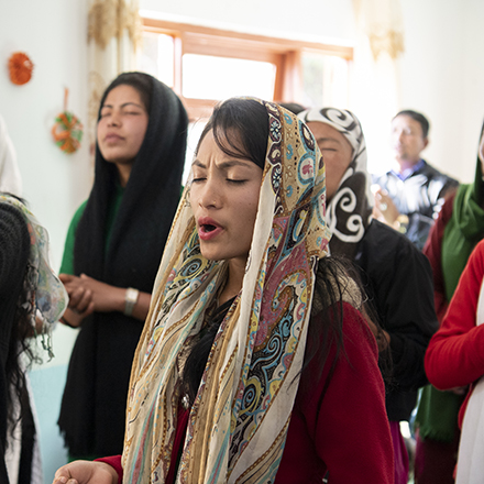 woman worshipping in a church with other women.